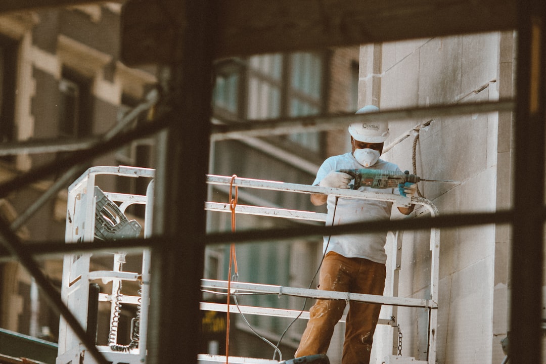 ベテラン職人が若手に外壁塗装の技術を指導している現場風景