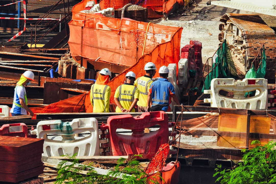 建設現場で図面を見ながら見積もりを検討する作業員たち