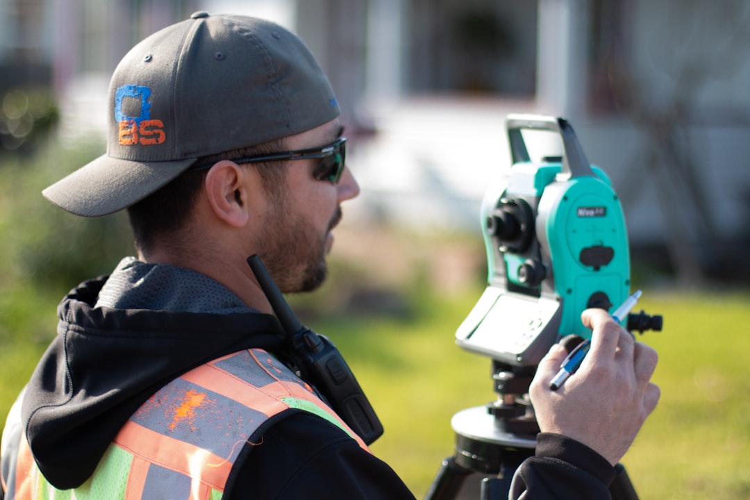 業者が住宅の外構部分を測量している現地調査の風景